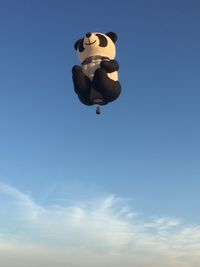 Low angle view of person paragliding against blue sky