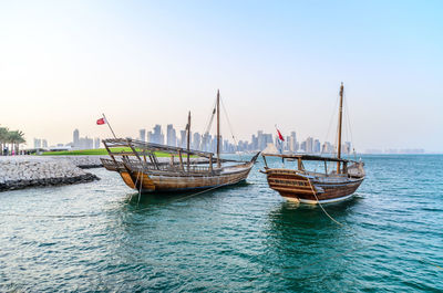 Sailboats moored on sea against clear sky