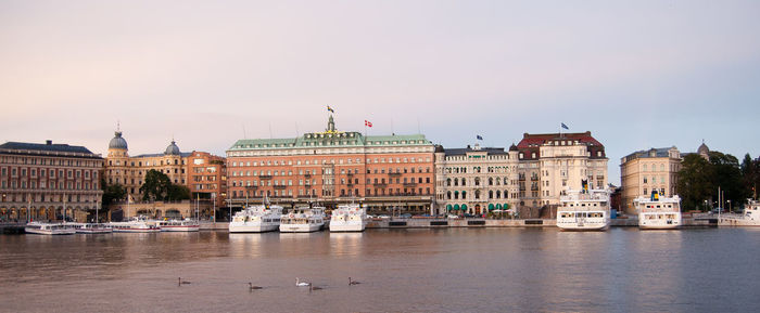 Boats moored in river against buildings in city