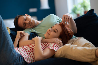 Side view of couple relaxing on bed at home