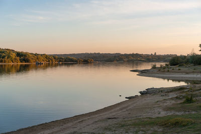 Scenic view of river against sky at sunset