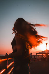 Side view of woman looking away against sky