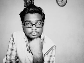 Portrait of young man in eyeglasses against wall