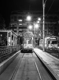 Train on illuminated street in city at night