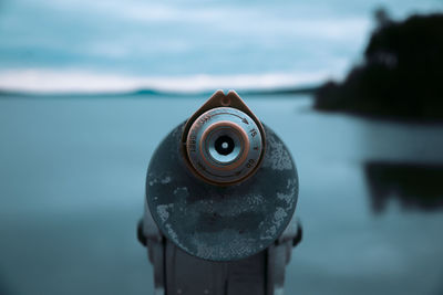 Close-up of coin-operated binoculars against sea