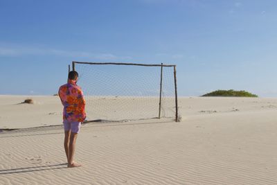 Rear view of man standing on beach against sky