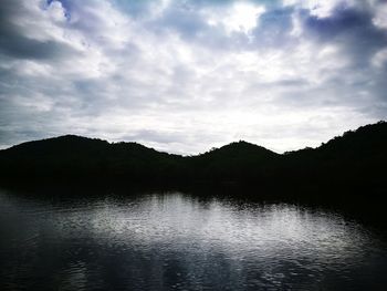 Scenic view of lake by silhouette mountain against sky