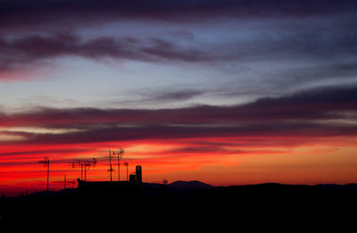 Silhouette electricity pylon against sky during sunset