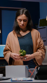 Portrait of young woman using mobile phone while sitting in office