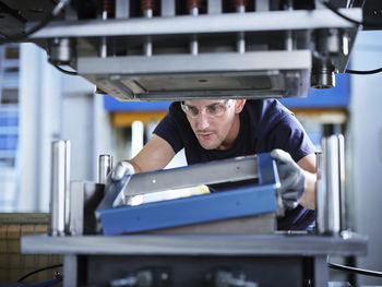 Technician wearing protective eyewear working with metal in factory