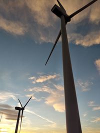 Low angle view of wind turbine against sky during sunset