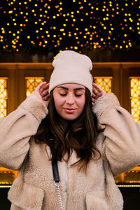 Young woman while standing against christmas decoration