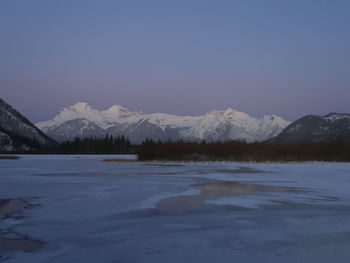 Scenic view of lake and snowcapped mountains against clear sky