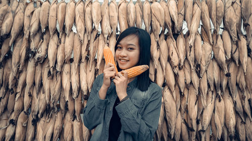 Portrait of smiling young woman standing infront of corn in the corn granary