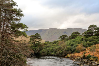 Scenic view of river by mountains against sky