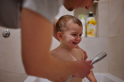 Cute little toddler having shower in bathtub
