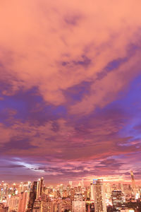 Aerial view of illuminated buildings in city against sky at sunset