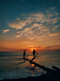 Silhouette men on beach against sky during sunset