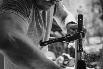 Man wood working using a drill and clamp with dust flying