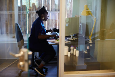 Side view of businesswoman using computer at desk in creative office