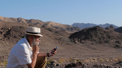 Senior man using mobile phone in the desert 