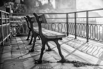 Empty bench on table by railing