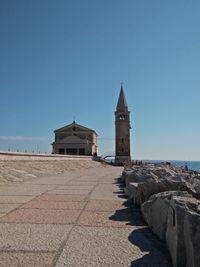 View of building by sea against clear blue sky