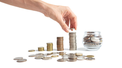 Close-up of hand holding coins over white background