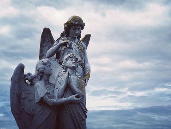 Low angle view of angel statues against sky