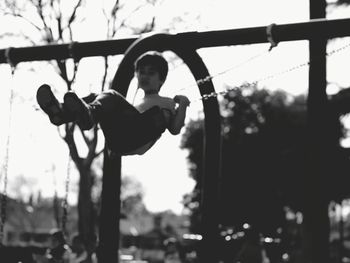 Low angle view of boy on swing against sky