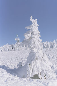 Snow covered land against clear blue sky