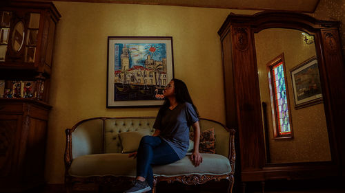 Young woman sitting on sofa at home