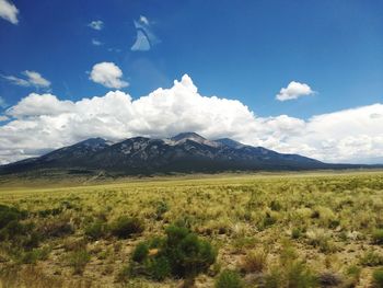 Scenic view of field and mountains against blue sky