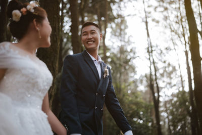 The newlyweds happy in the atmosphere of the pine forest, looking and feeling warm.