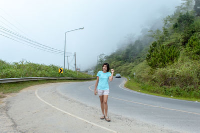 Full length of woman standing on road against sky