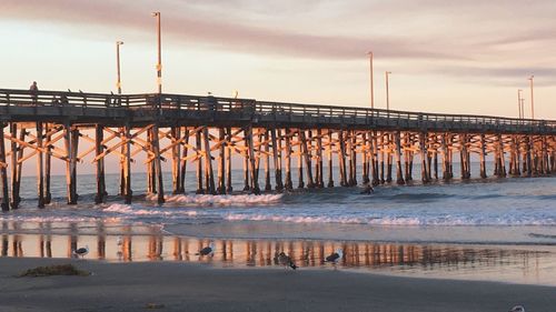 Bridge over sea against sky during sunset