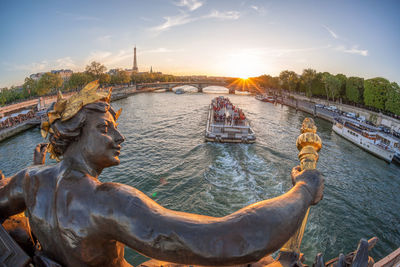 Close-up of statue against river in city during sunset