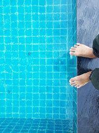 Low section of person standing by swimming pool