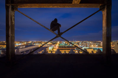 Silhouette man working at illuminated city against sky at night