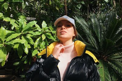 Portrait of young woman standing against plants