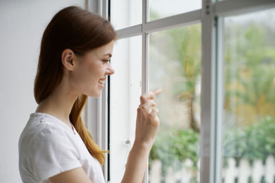 Portrait of young woman looking through window