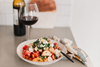 Italian pancanella salad in deep plate. fresh heirloom tomatoes. red wine in glass.