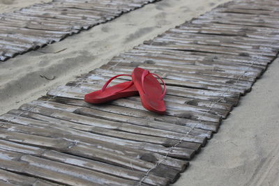 High angle view of flip-flops on boardwalk over sand
