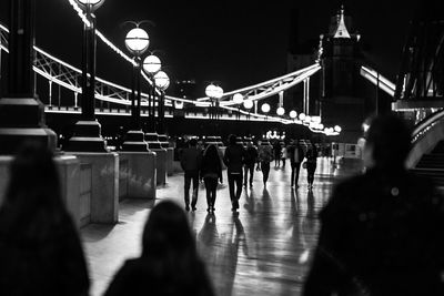 People walking on bridge in city at night