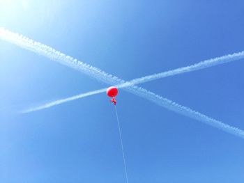Low angle view of red balloon flying against blue sky during sunny day