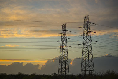 Silhouette electricity pylon against sky during sunset