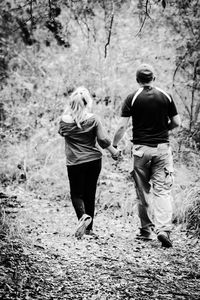 Rear view of man and woman walking in forest