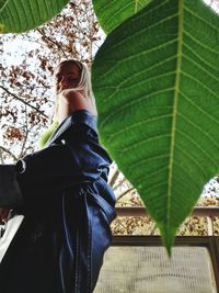 Low angle view of woman with leaves against trees