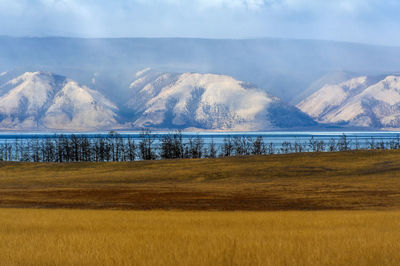 Scenic view of field by lake against sky