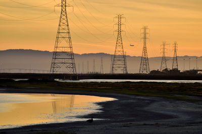 Silhouette of electricity pylon against sky during sunset